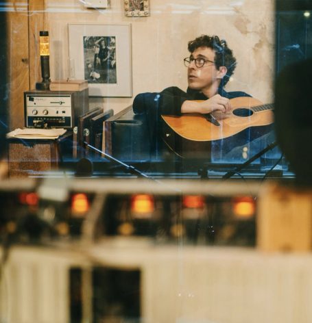 Man with guitar in the studio looking right